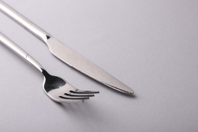 Stylish cutlery. Silver knife and fork on gray background, closeup. Space for text