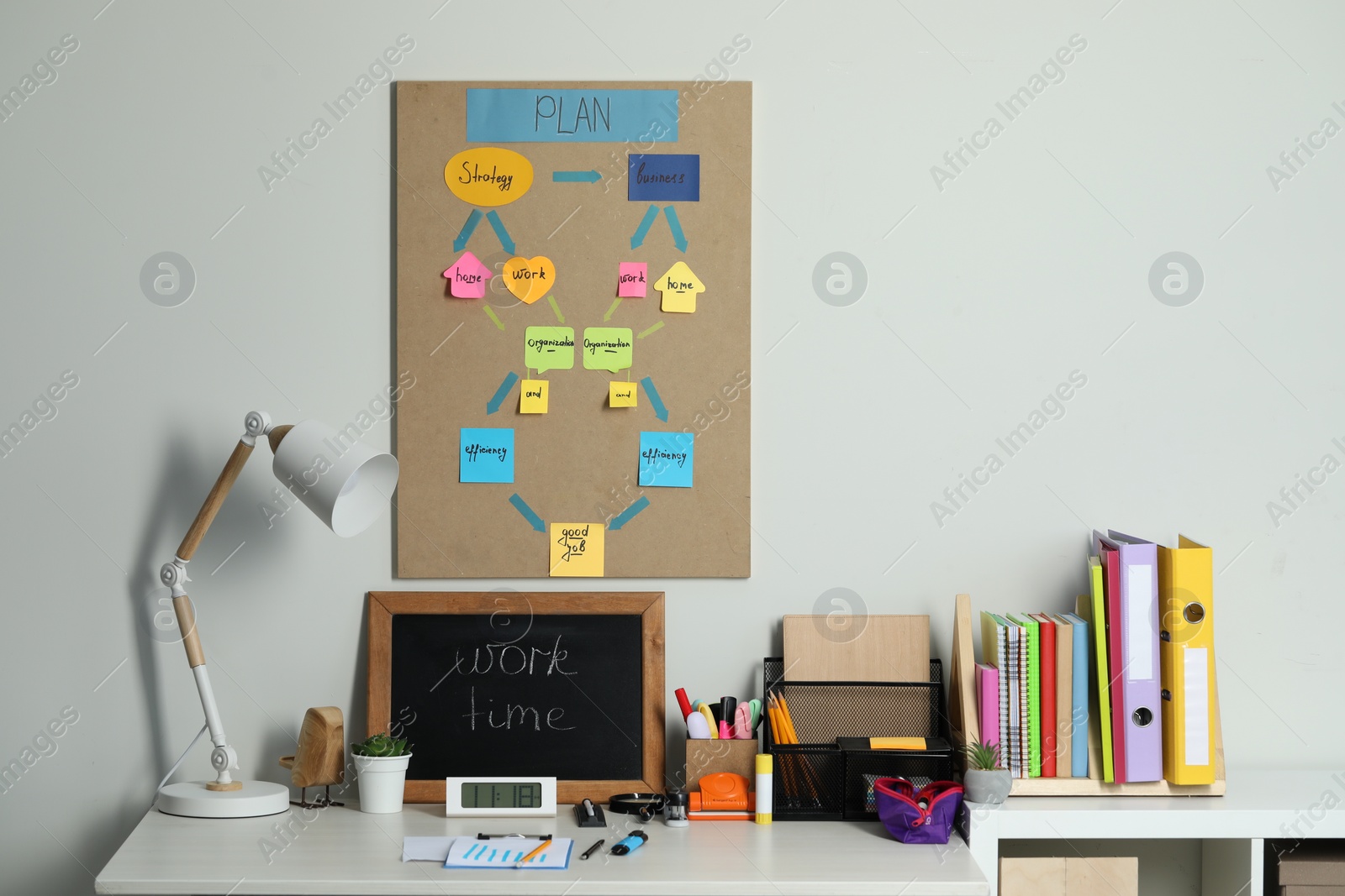 Photo of Business process planning and optimization. Workplace with lamp, small blackboard, colorful paper notes and other stationery on white wooden table