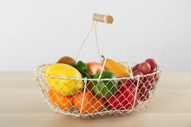 Photo of Fresh ripe fruits in metal basket on wooden table