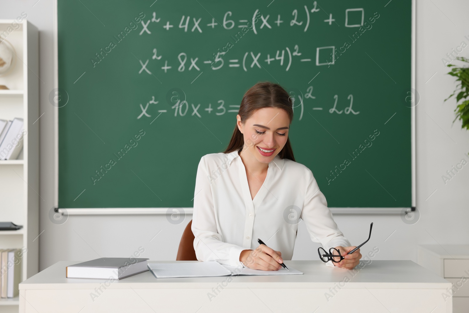 Photo of Young math’s teacher giving lesson at table in classroom