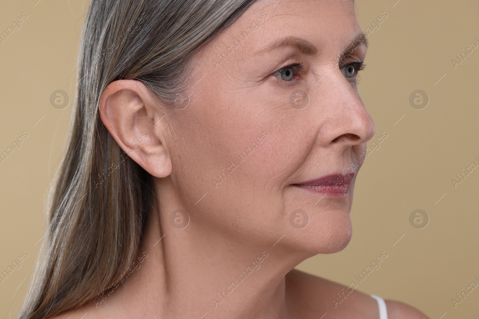 Photo of Portrait of senior woman with aging skin on beige background. Rejuvenation treatment