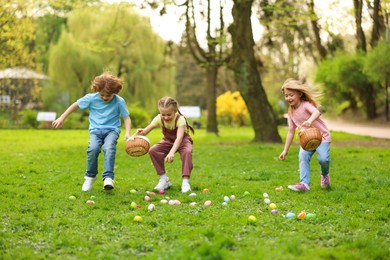 Photo of Easter celebration. Cute little children hunting eggs outdoors