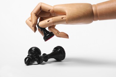 Robot holding pawn over other chess pieces on white background. Wooden hand representing artificial intelligence