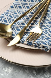 Clean plates, cutlery and napkin on light grey textured table, closeup