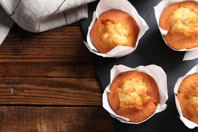 Photo of Delicious sweet muffins on wooden table, top view. Space for text