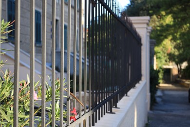 Black metal fence with columns near building on city street, closeup