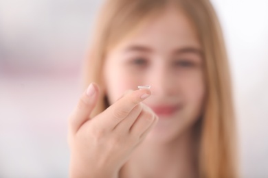 Photo of Teenage girl with contact lens on blurred background