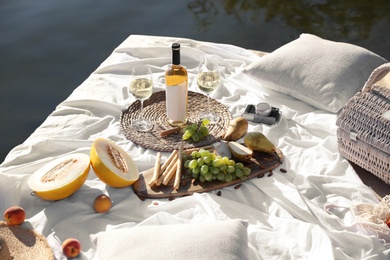 Picnic blanket with delicious food and wine on pier