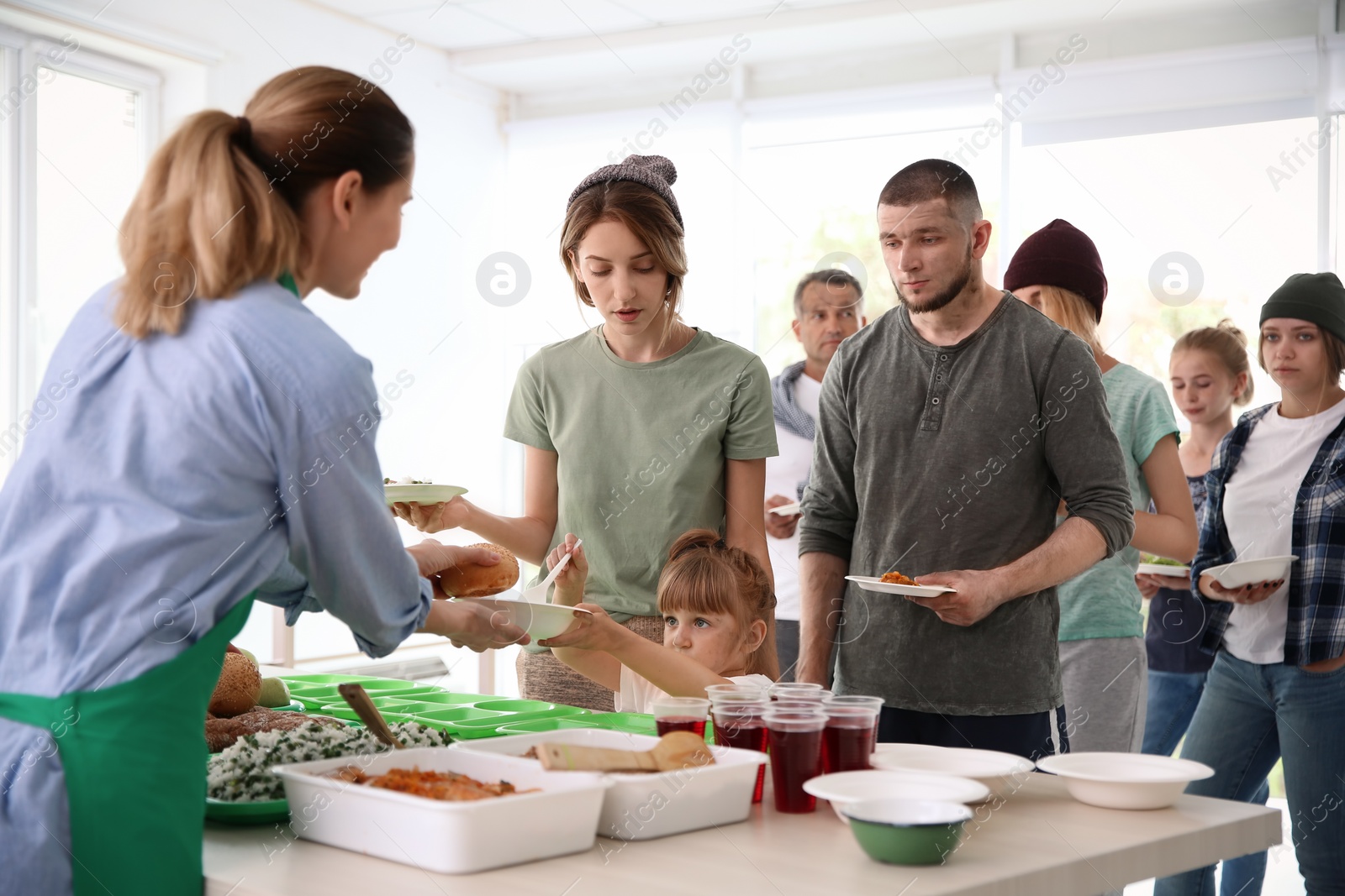 Photo of Volunteers serving food for poor people indoors