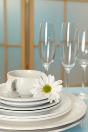 Photo of Set of clean dishware and flower on light blue table, closeup