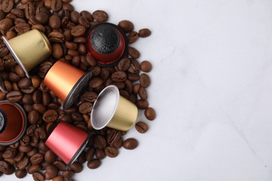 Photo of Many coffee capsules and beans on white marble table, above view. Space for text