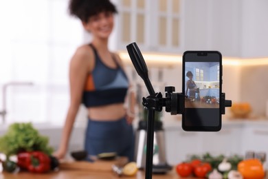 Photo of Food blogger recording video in kitchen, focus on smartphone