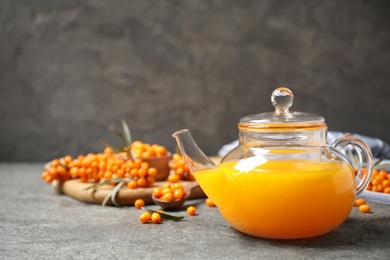 Photo of Delicious sea buckthorn tea and fresh berries on grey table. Space for text