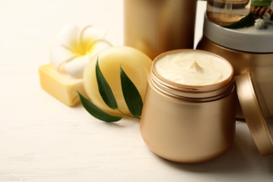 Set of hair cosmetic products and flowers on white wooden table, closeup