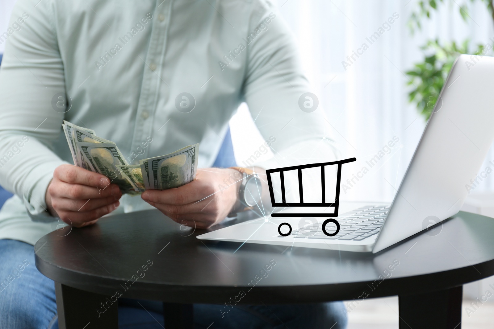 Image of Online shopping. Cart illustration near laptop and man counting money indoors