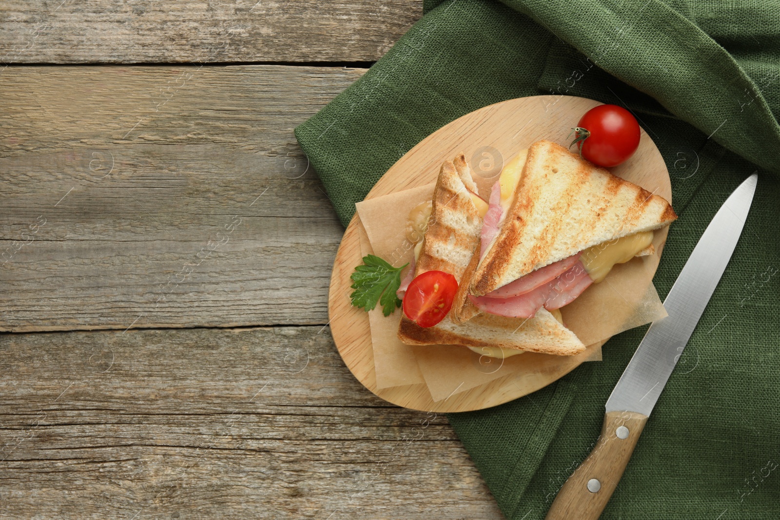 Photo of Tasty sandwiches with ham, tomato, parsley and melted cheese on wooden table, flat lay. Space for text