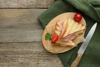 Photo of Tasty sandwiches with ham, tomato, parsley and melted cheese on wooden table, flat lay. Space for text