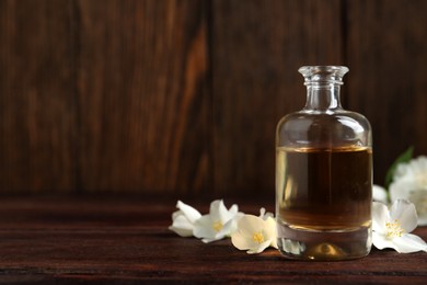 Essential oil and jasmine flowers on wooden table. Space for text