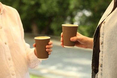 Women holding takeaway paper cups outdoors, closeup. Coffee to go