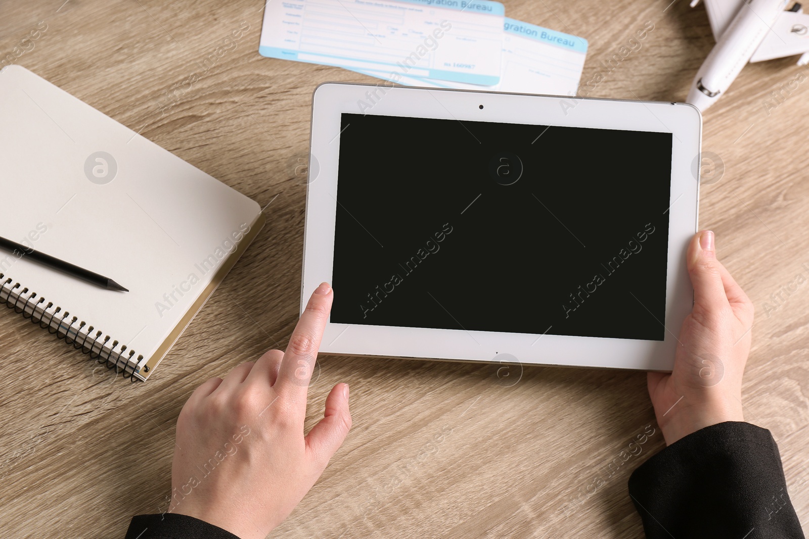 Photo of Woman holding tablet with blank screen over table, closeup. Travel agency