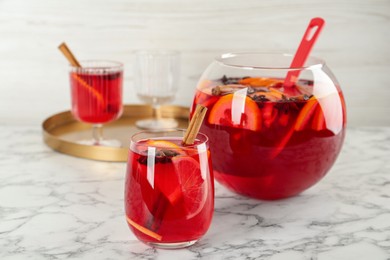 Photo of Glass and bowl of delicious aromatic punch drink on white marble table