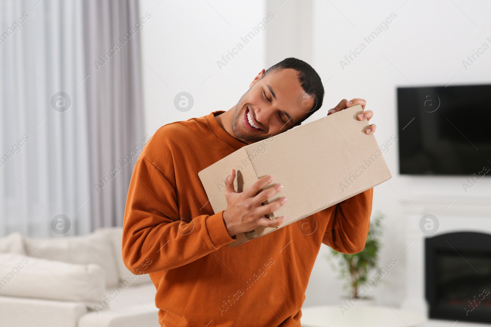 Photo of Happy young man with parcel at home. Internet shopping