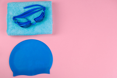 Flat lay composition with swimming accessories on pink background. Space for text