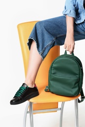 Photo of Woman in stylish shoes with backpack on chair against white background, closeup