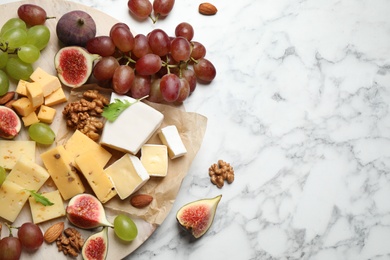 Set of different snacks with ripe figs served on marble table, flat lay. Space for text