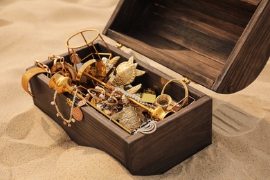 Photo of Open wooden chest with treasures on sand