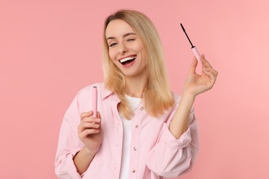 Beautiful woman with mascara on pink background