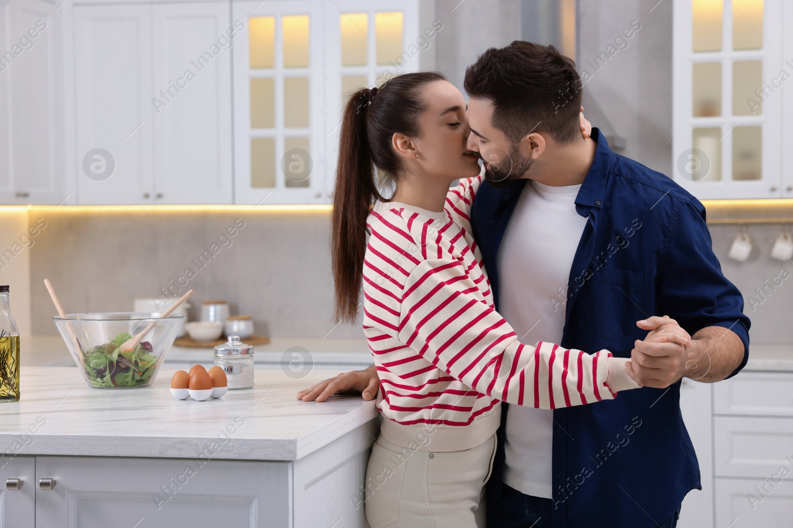 Photo of Lovely young couple kissing together in kitchen