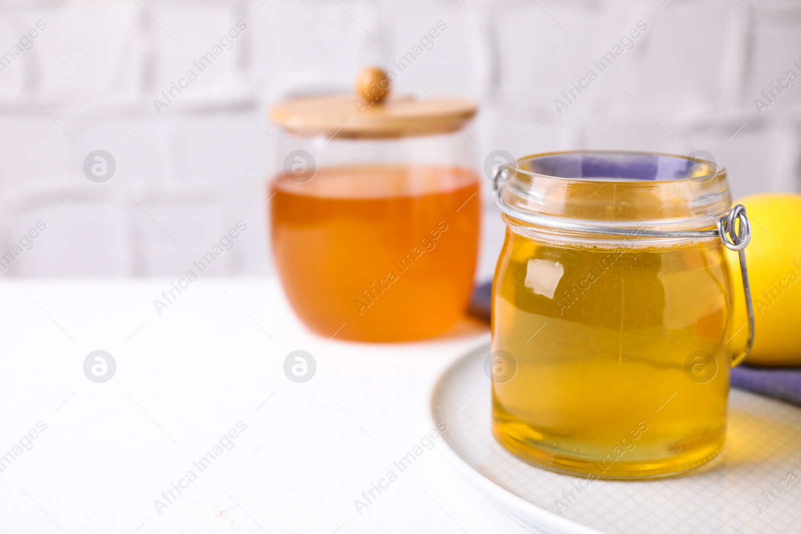 Photo of Tasty aromatic honey on white table, space for text