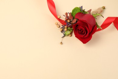 Photo of Stylish boutonniere with red rose and ribbon on beige background. Space for text