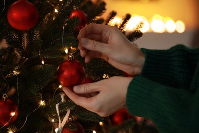 Photo of Woman decorating Christmas tree at home, closeup
