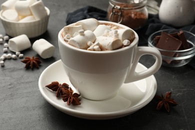 Photo of Tasty hot chocolate with marshmallows on dark textured table, closeup