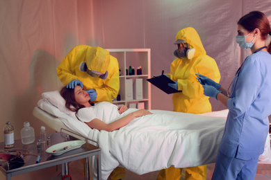 Photo of Professional paramedics examining patient with virus in quarantine ward