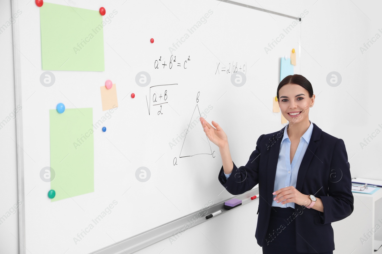 Photo of Young teacher near whiteboard in modern classroom