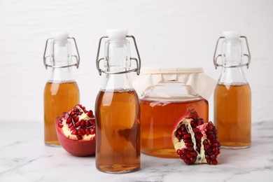 Photo of Tasty kombucha and pomegranate on white marble table