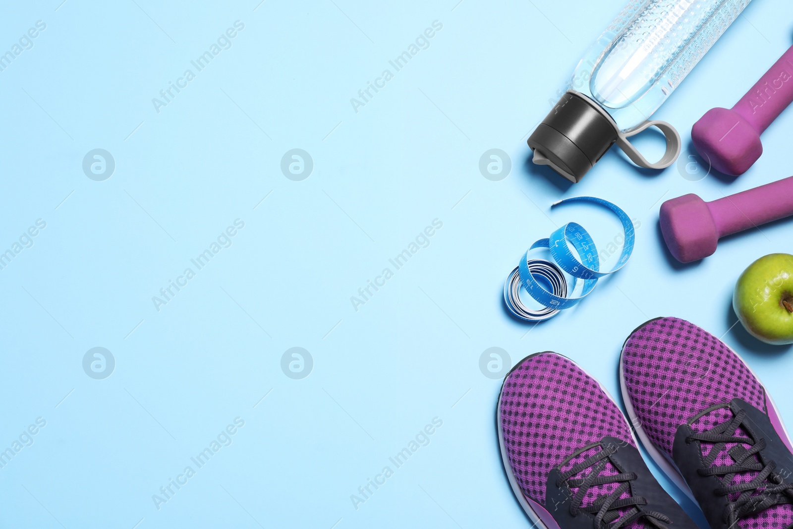Photo of Flat lay composition with sneakers and dumbbells on light blue background. Space for text
