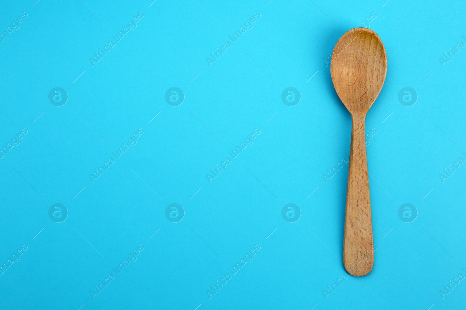 Photo of Clean empty wooden spoon on blue background, top view. Space for text