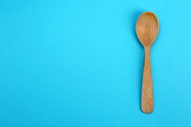 Photo of Clean empty wooden spoon on blue background, top view. Space for text