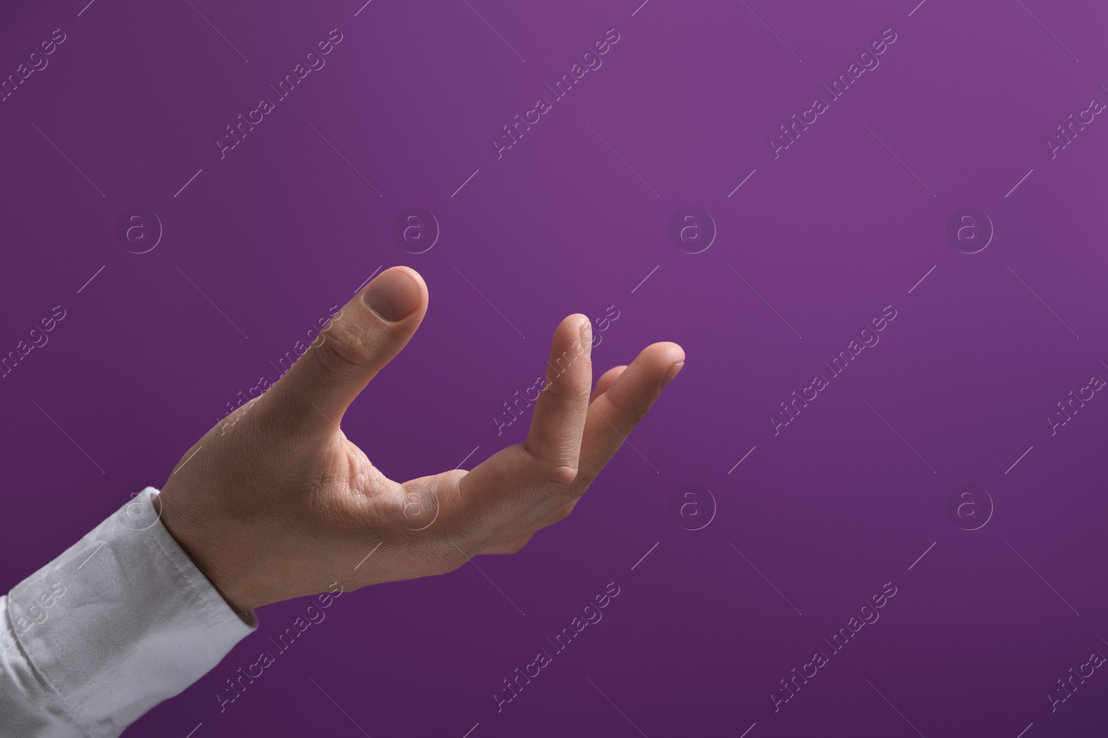 Photo of Man holding something in hand on purple background, closeup. Space for text