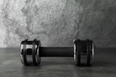 Photo of Metal dumbbell on table against grey background. Space for text