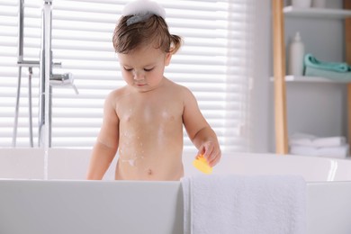 Photo of Cute little girl taking bath with toy indoors