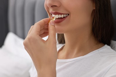 Woman taking vitamin pill at home, closeup