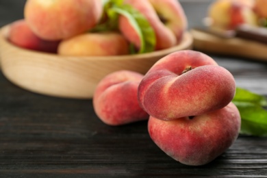 Photo of Fresh ripe donut peaches on black wooden table, closeup