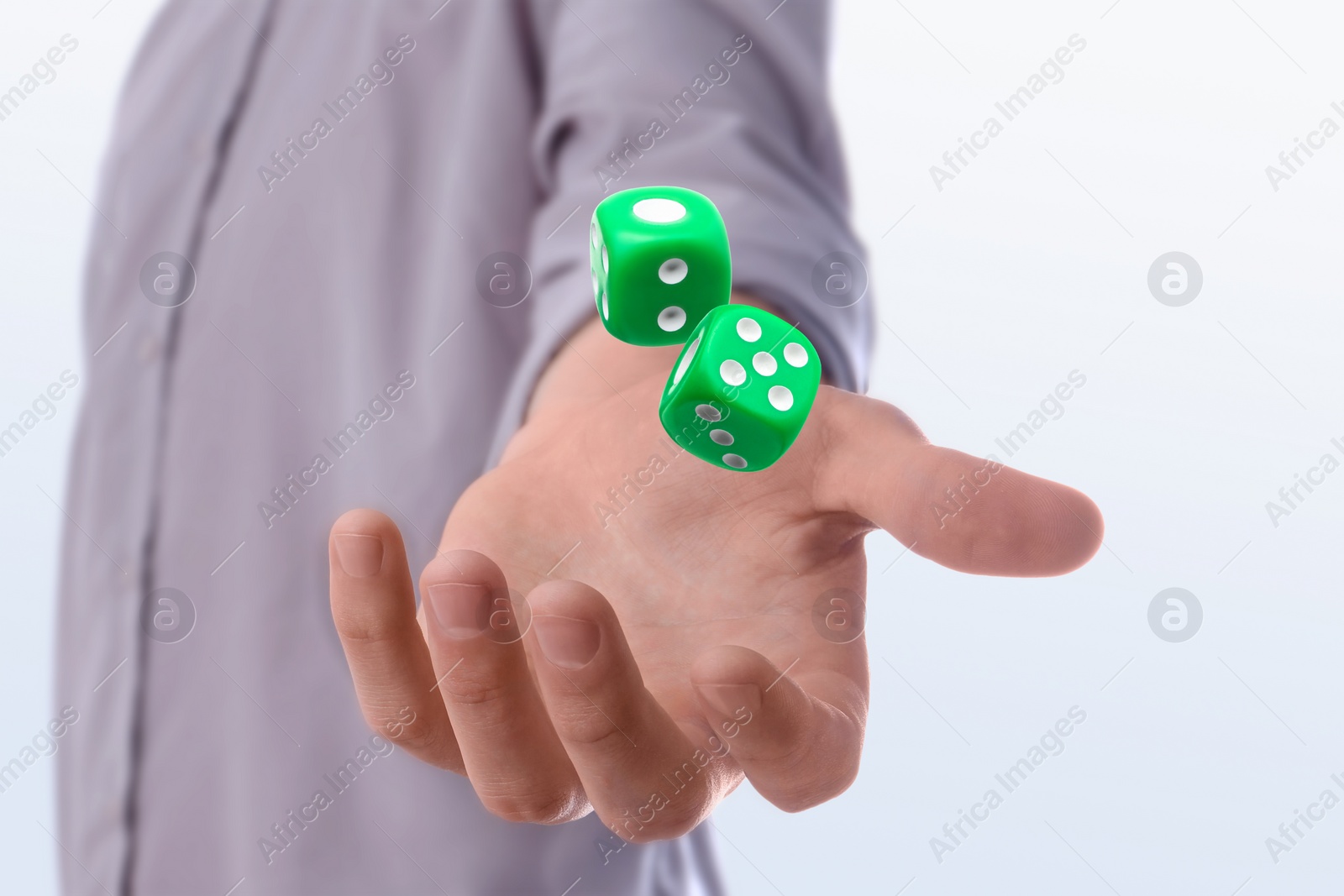 Image of Man throwing green dice on white background, closeup