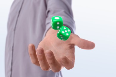 Man throwing green dice on white background, closeup