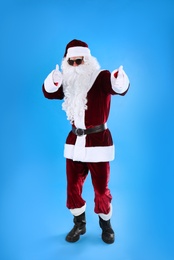 Full length portrait of Santa Claus with sunglasses on light blue background